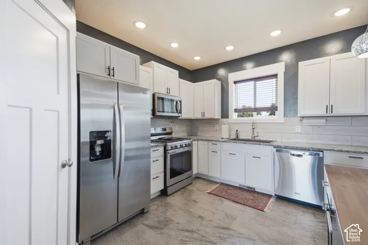 Kitchen featuring stainless steel appliances, white cabinetry, recessed lighting, and stone countertops
