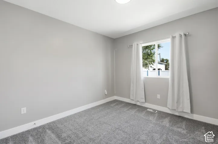 Light gray walls, gray carpet, and a single window with white trim