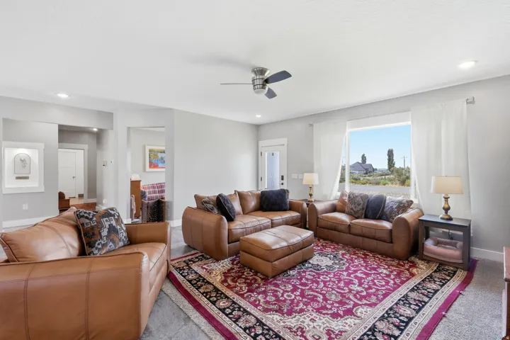 Recessed lighting, ceiling fan, large window, light gray walls, and wood-finish flooring