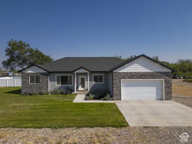 Ranch-style residence featuring a dark shingle roof, stone and stucco exterior, and white vinyl siding accents