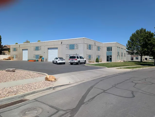 Commercial building with multiple roll-up doors, an asphalt parking area, and a landscaped frontage
