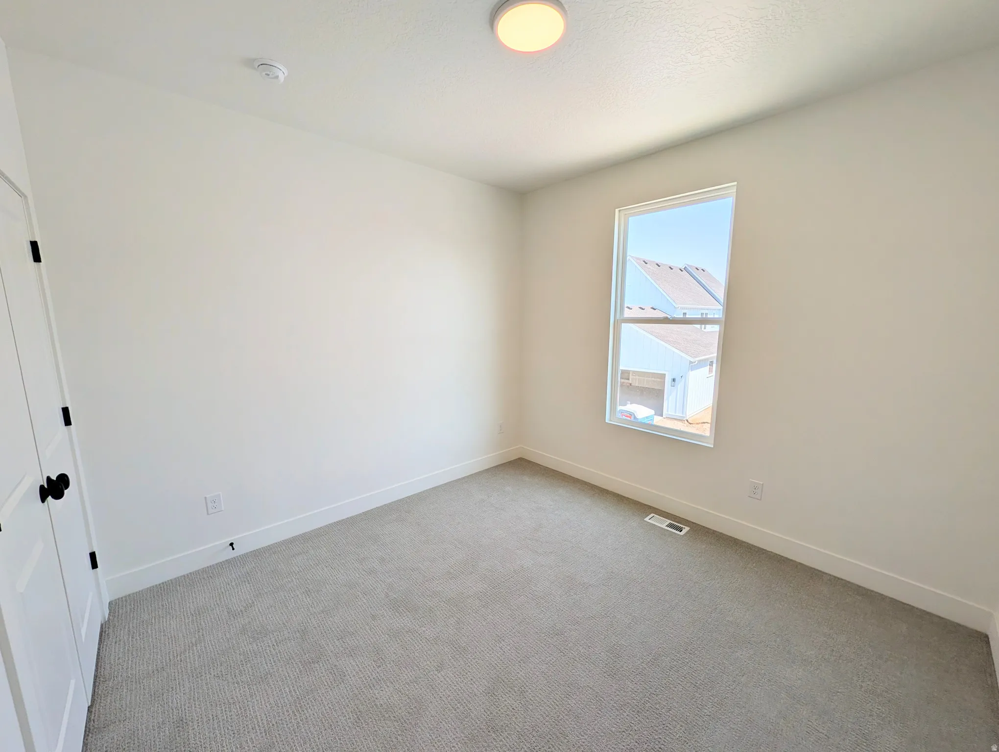 Neutral wall paint with white trim, gray carpet flooring, and a single window