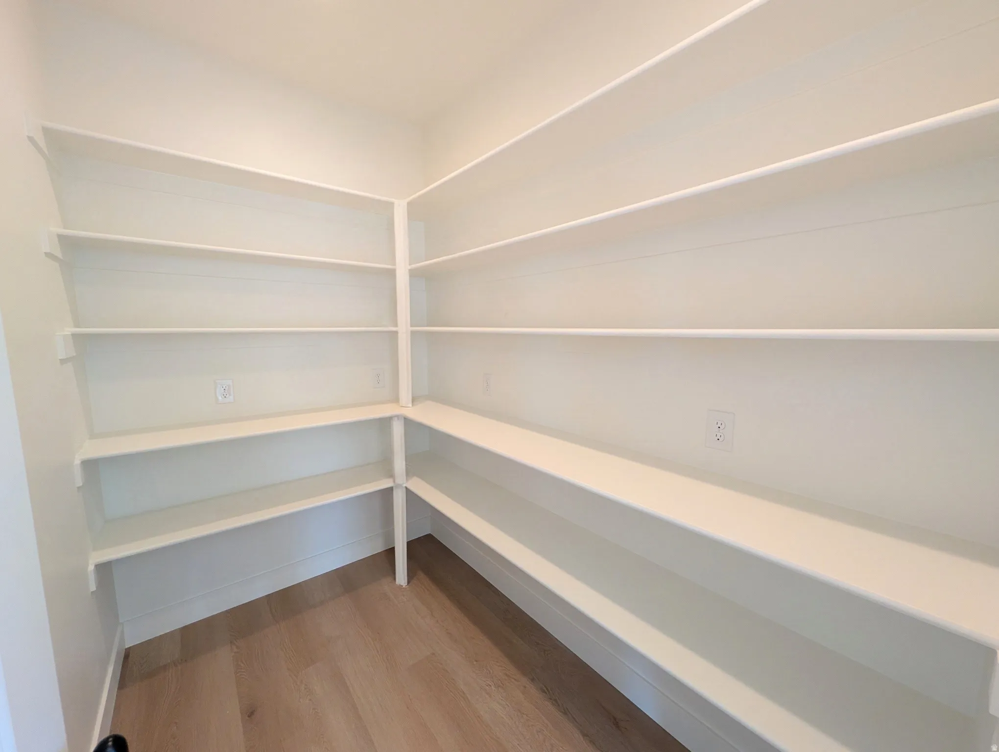 Extensive built-in shelving providing ample storage, light-toned wood-finish flooring, and multiple electrical outlets