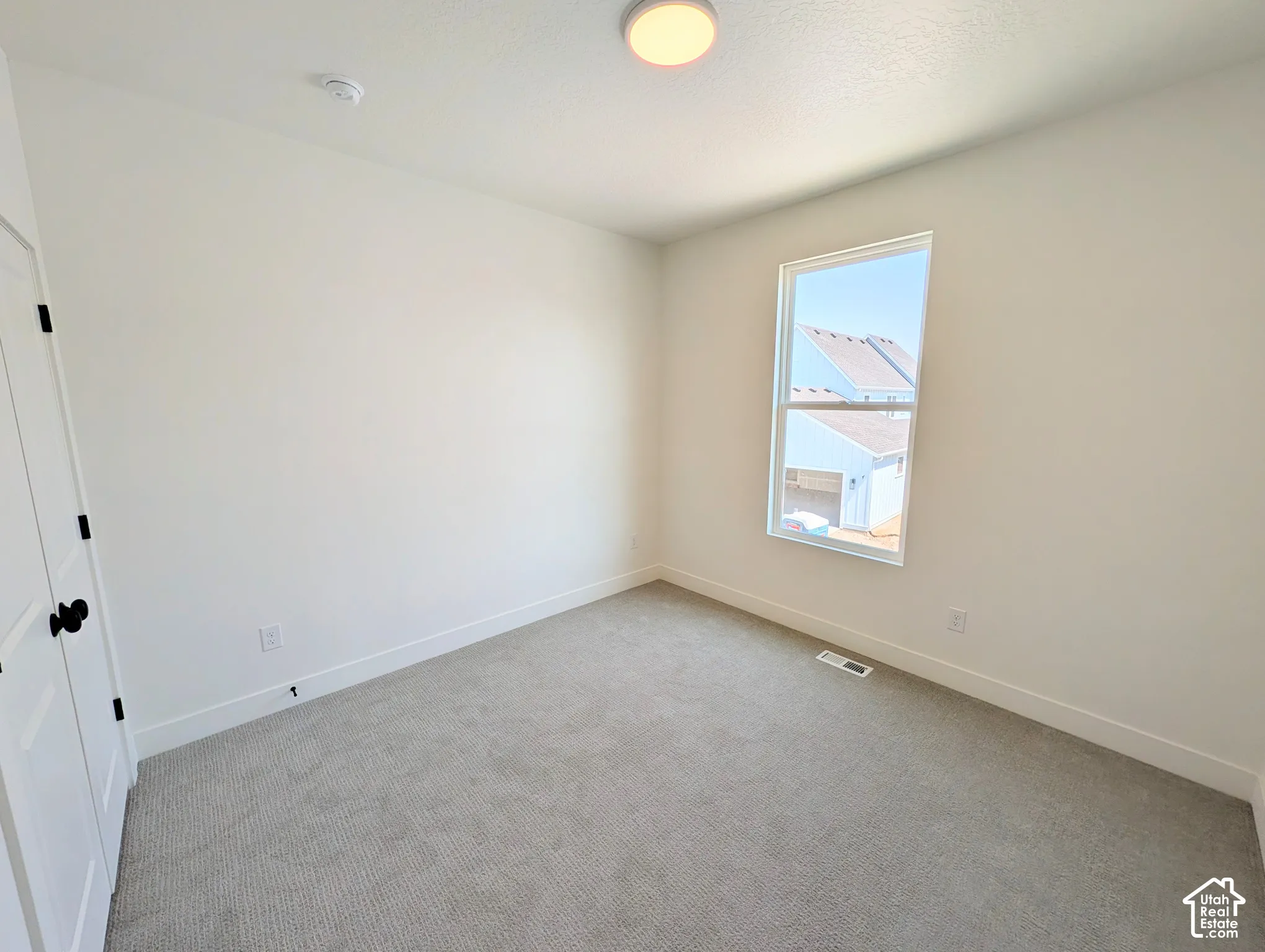 Neutral wall paint with white trim, gray carpet flooring, and a single window