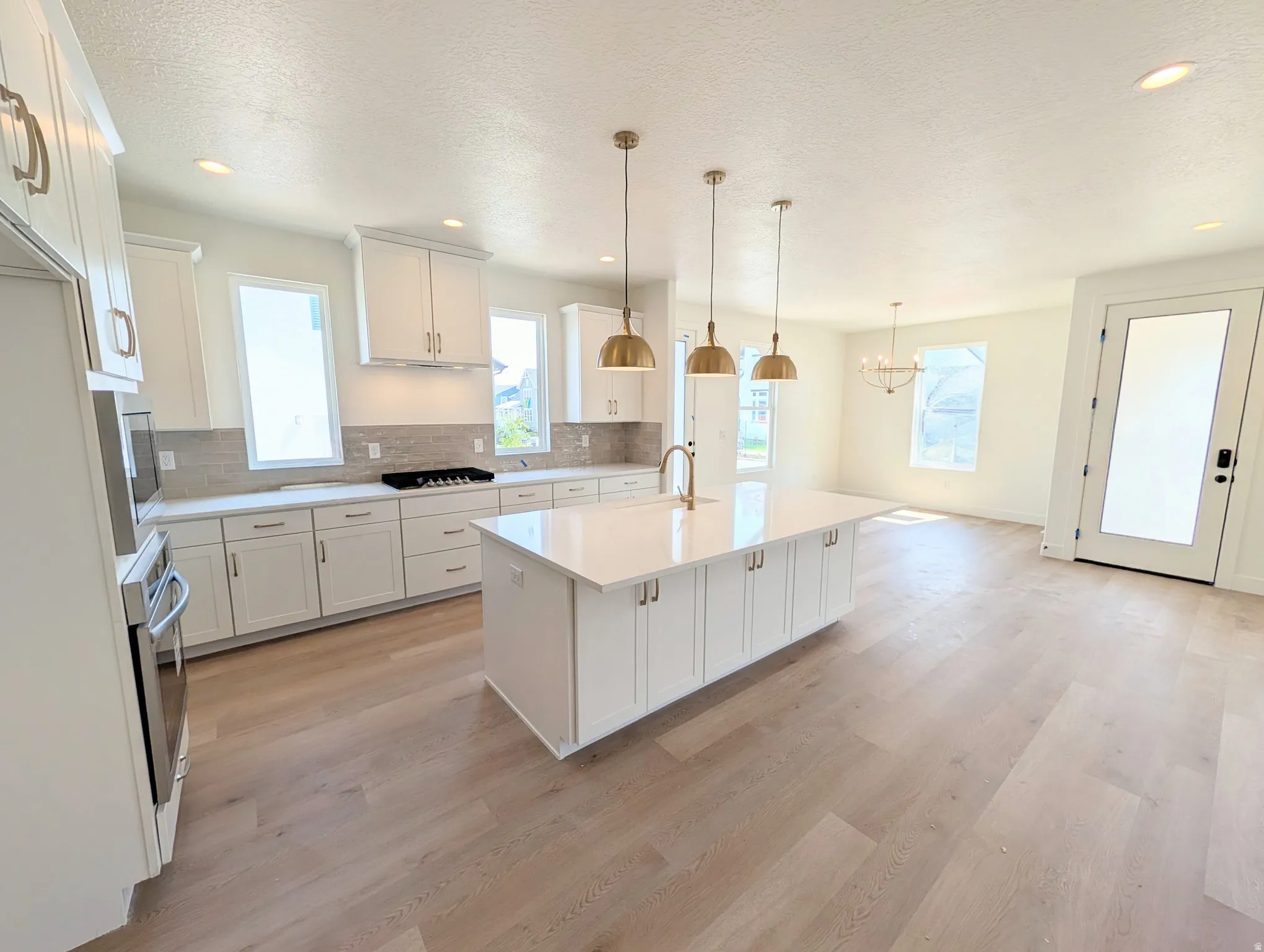 Spacious kitchen featuring white cabinetry, a large center island, and wood-finish flooring