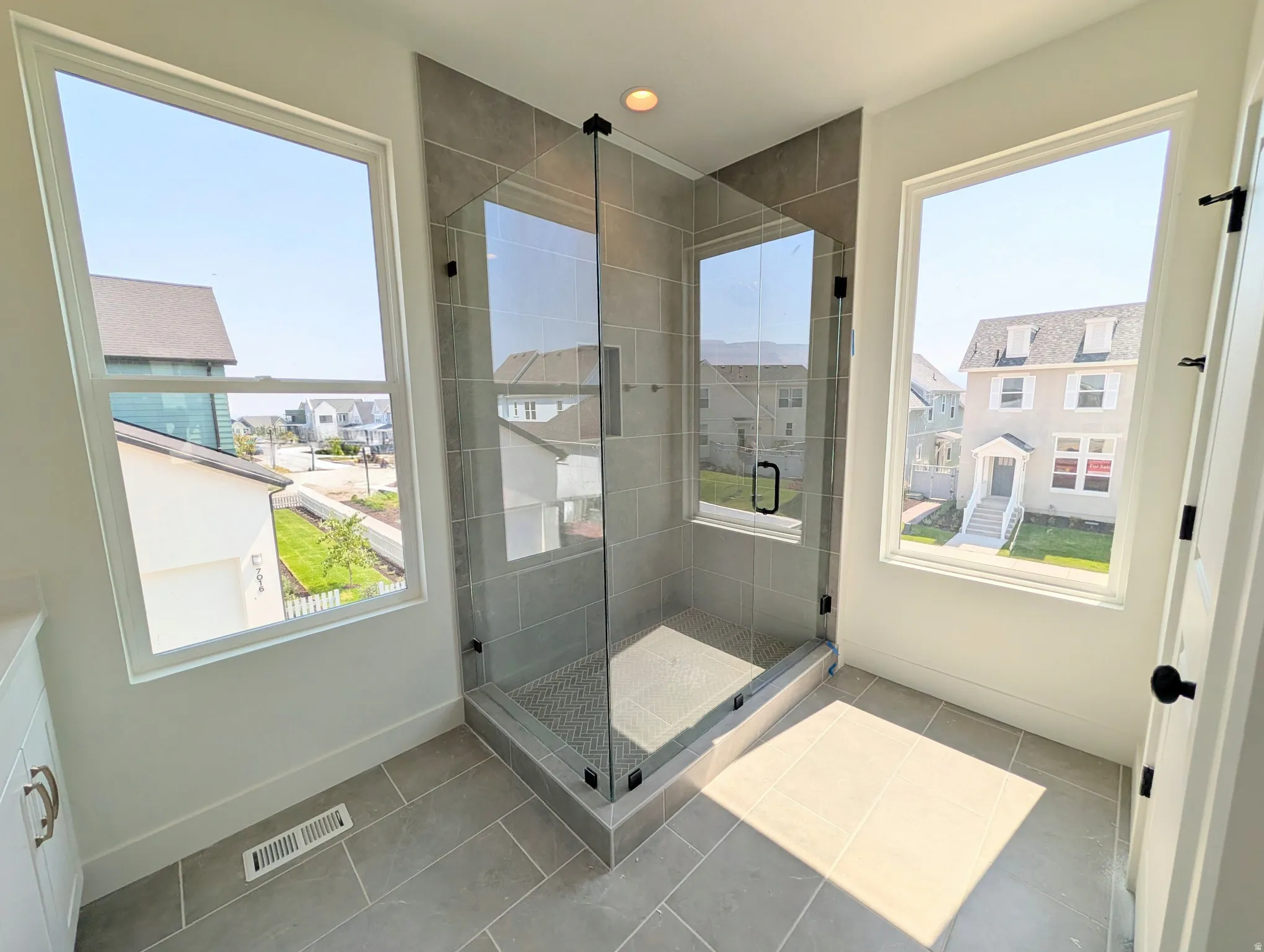 Expansive walk-in shower with floor-to-ceiling tile, glass enclosure, and recessed lighting