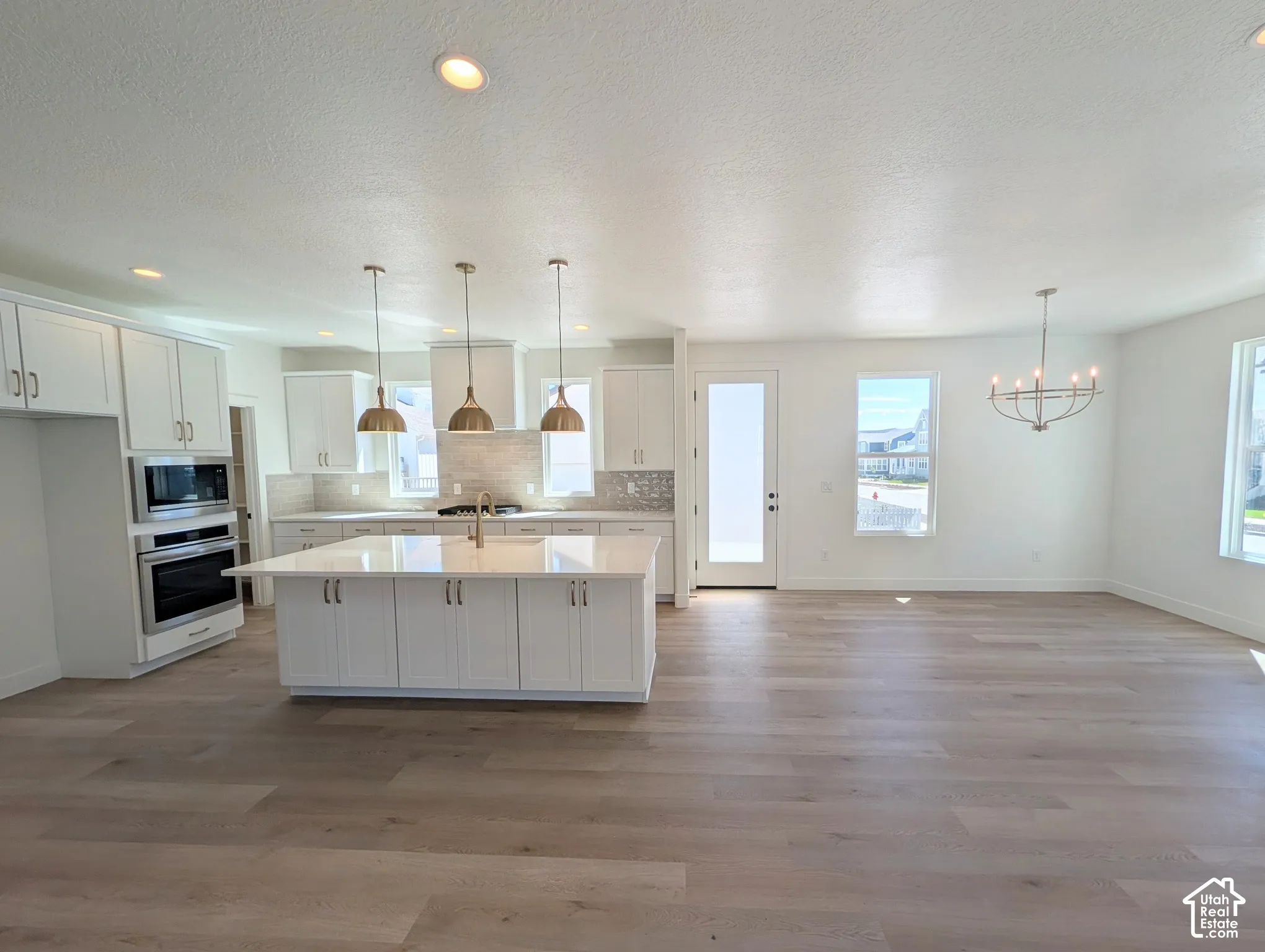 Open-concept living area featuring wood-finish flooring, recessed lighting, and a modern chandelier