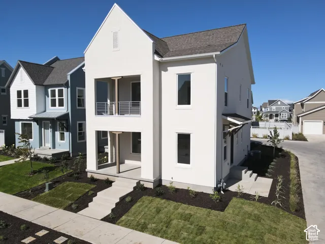 Contemporary two-story exterior with a stucco finish, a covered entry, and a second-story balcony with metal railings