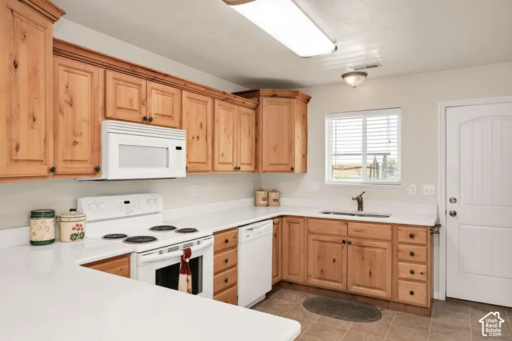 Wood cabinetry with dark hardware, white countertops and white applliances