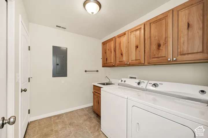 Utility room featuring tiled flooring, wood-finish cabinetry and a single basin sink