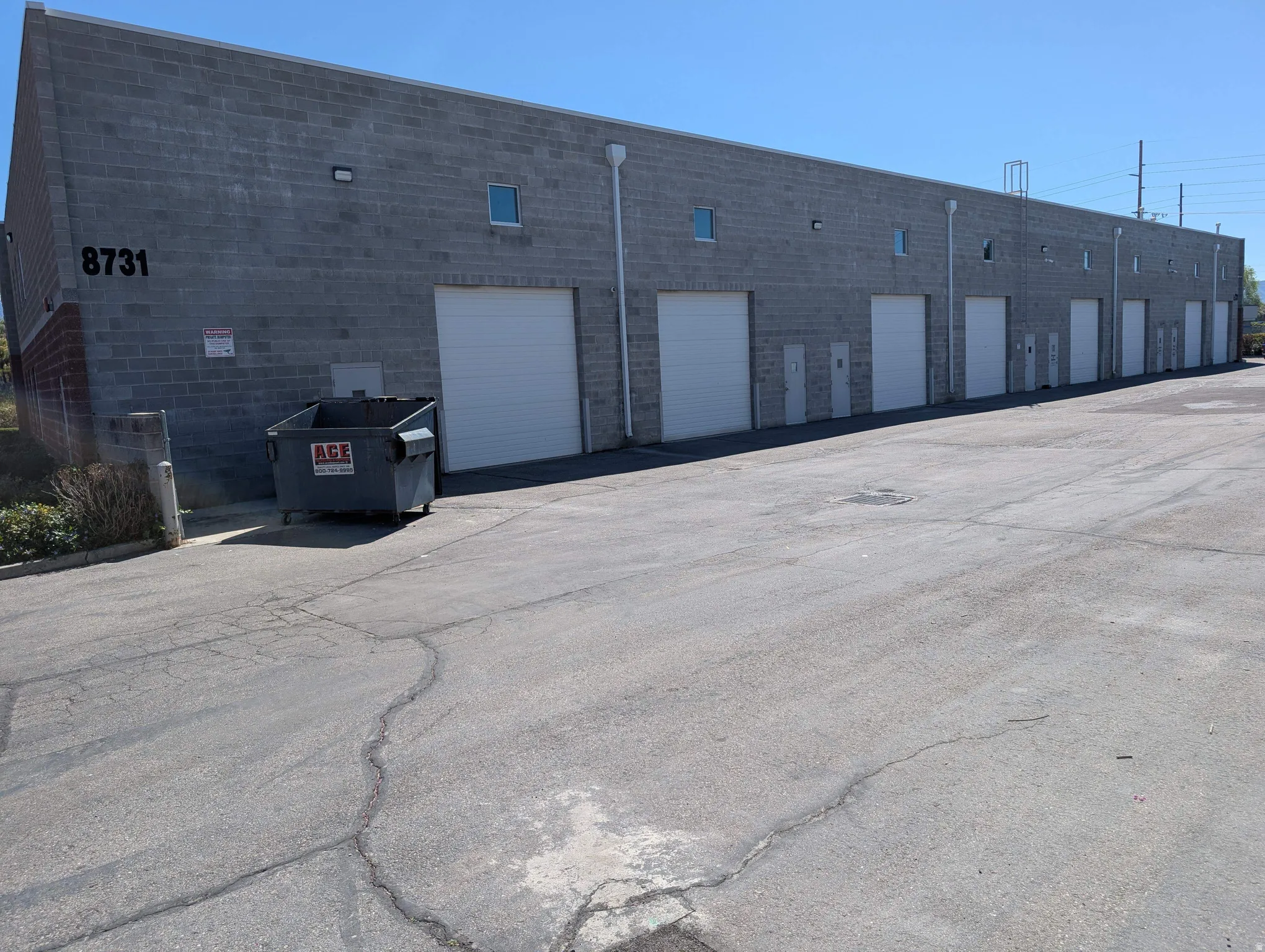 Concrete block construction with multiple roll-up doors, individual access doors, and exterior lighting fixtures