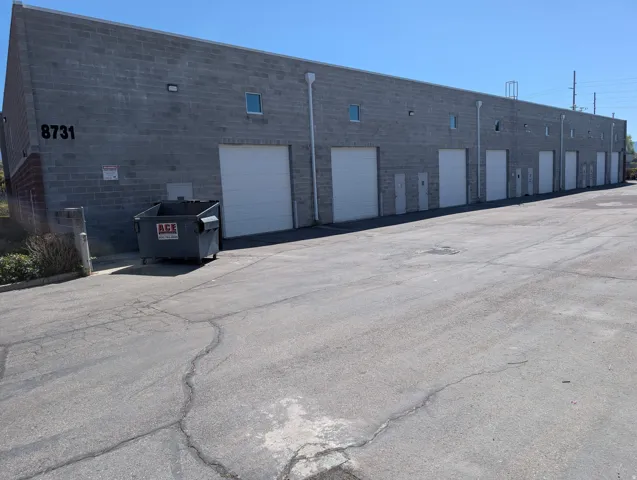 Concrete block construction with multiple roll-up doors, individual access doors, and exterior lighting fixtures