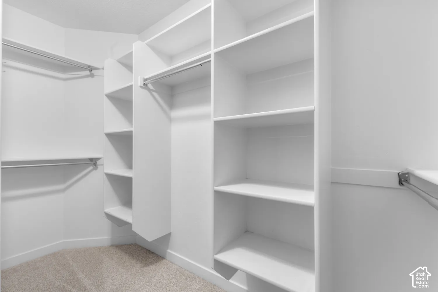 Walk-in closet featuring built-in shelving, multiple hanging rods, and carpet flooring