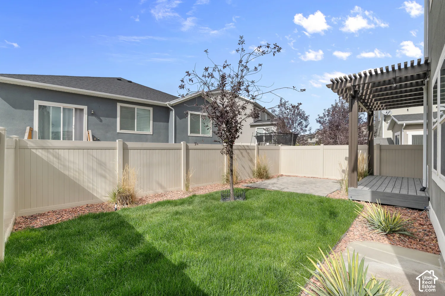 Enclosed backyard featuring a manicured lawn, a concrete patio area, and a composite deck with an overhead pergola