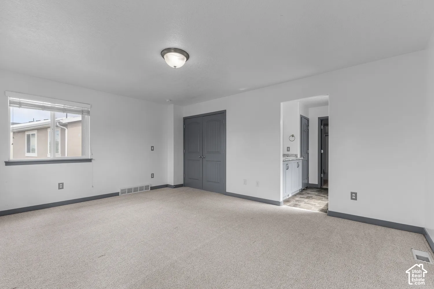 Carpeted flooring, window with blinds, ceiling-mounted light fixture, painted double doors, and a wet bar with cabinetry