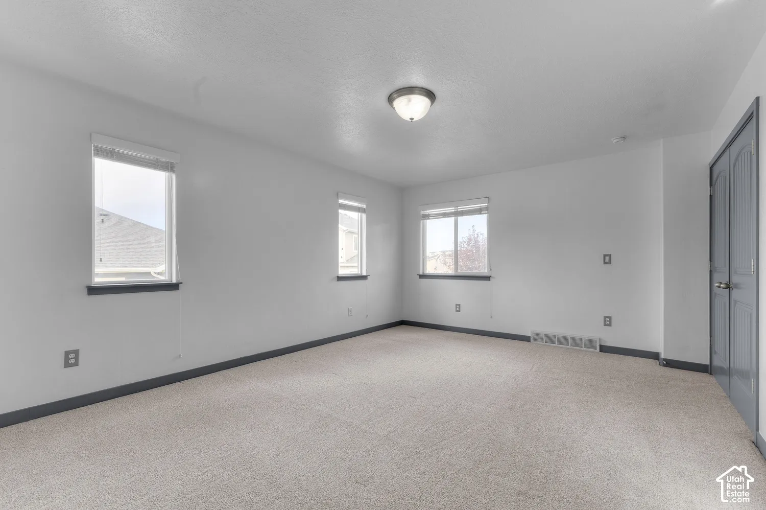Carpeted flooring, multiple windows, flush mount ceiling light fixture, and bifold door