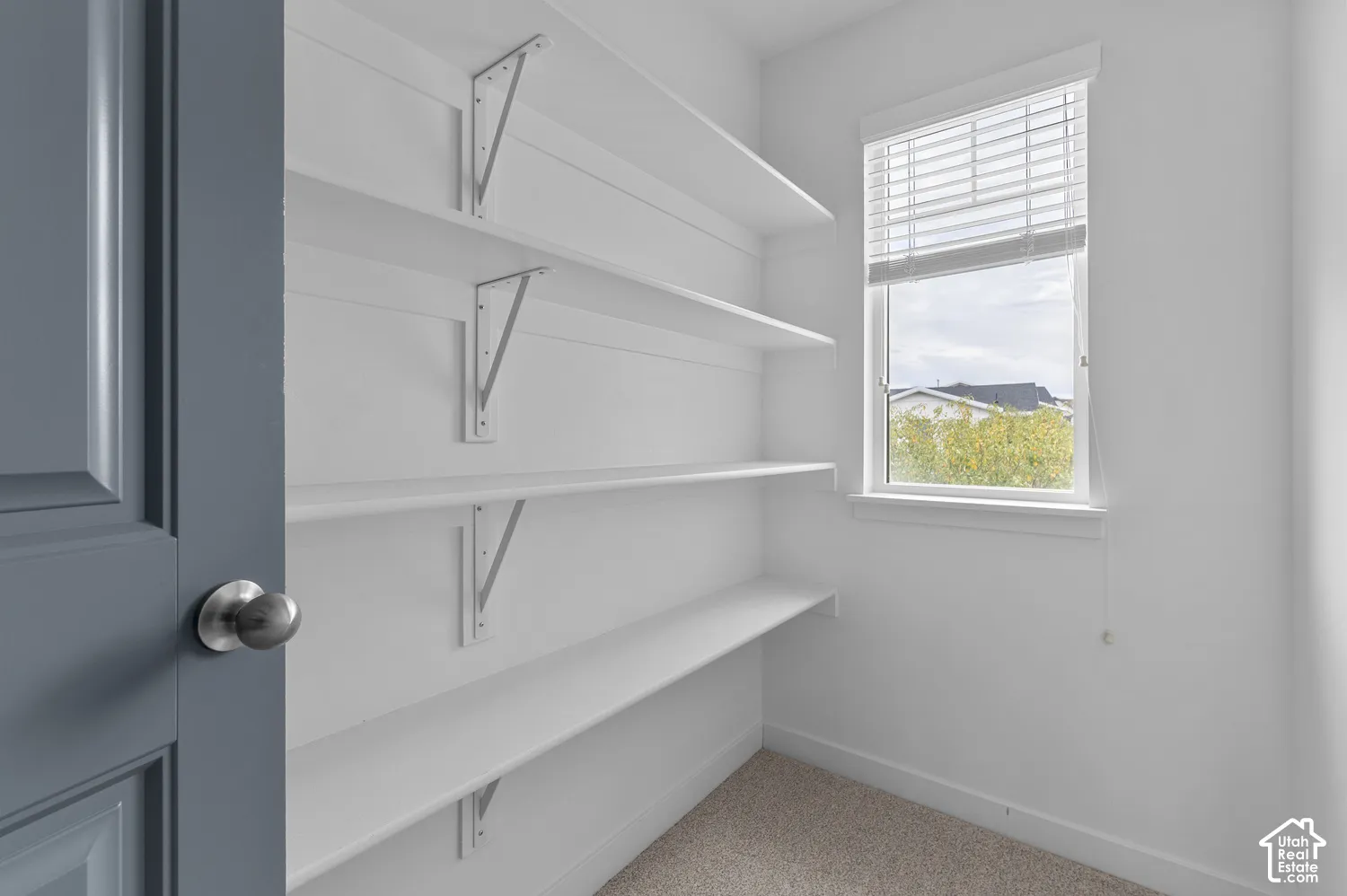 Built-in shelving with brackets, window with blinds, and neutral wall paint