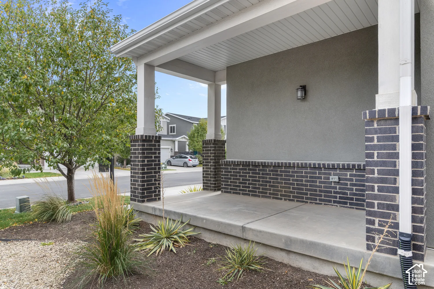 Covered front porch featuring dark brick accents and a stucco exterior