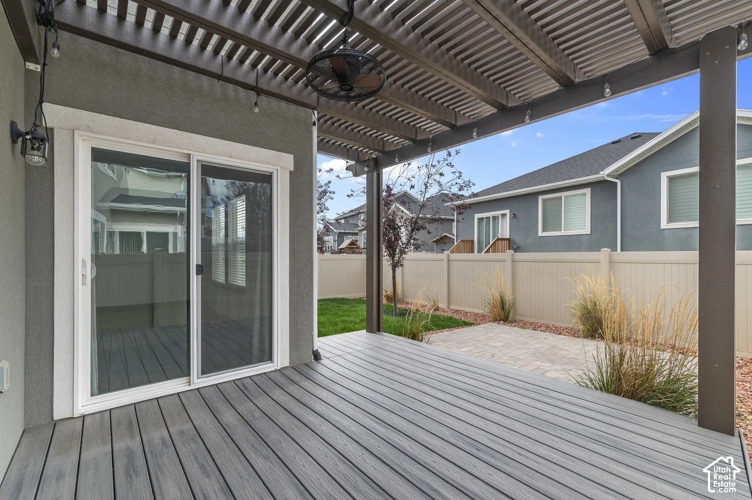 Covered patio with louvered aluminum pergola overhead, composite decking, and glass sliding doors opening to the home