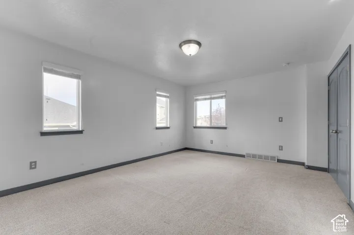 Carpeted flooring, multiple windows, flush mount ceiling light fixture, and bifold door