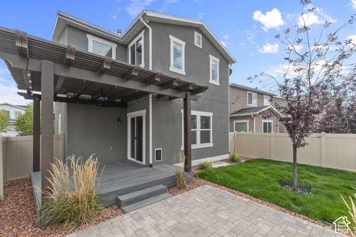 Private backyard featuring a paver patio, wood-finish pergola, and a grassy area