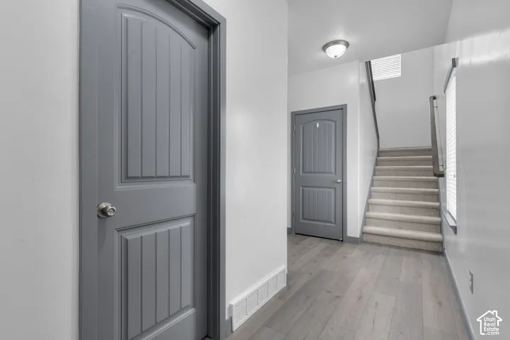 Light gray wood-finish flooring, white walls, gray interior doors with arched top panels, and a carpeted staircase