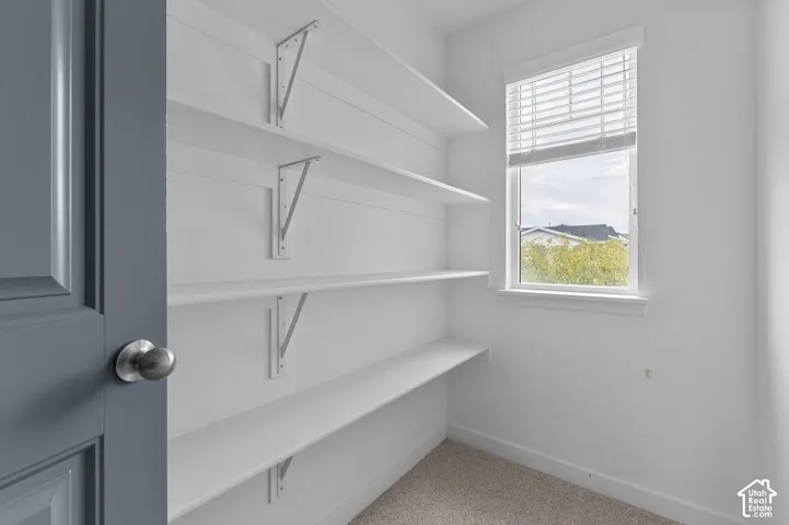 Built-in shelving with brackets, window with blinds, and neutral wall paint