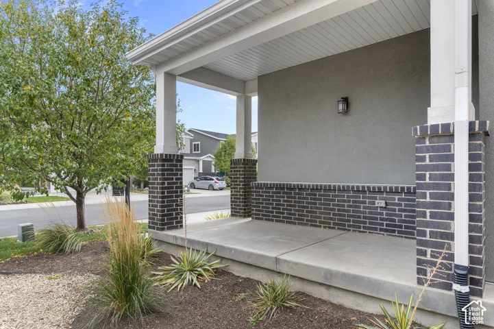 Covered front porch featuring dark brick accents and a stucco exterior