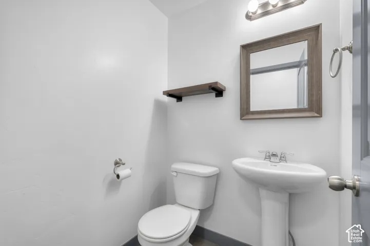 Pedestal sink with chrome faucet, framed mirror with vanity lighting, and wall-mounted shelving