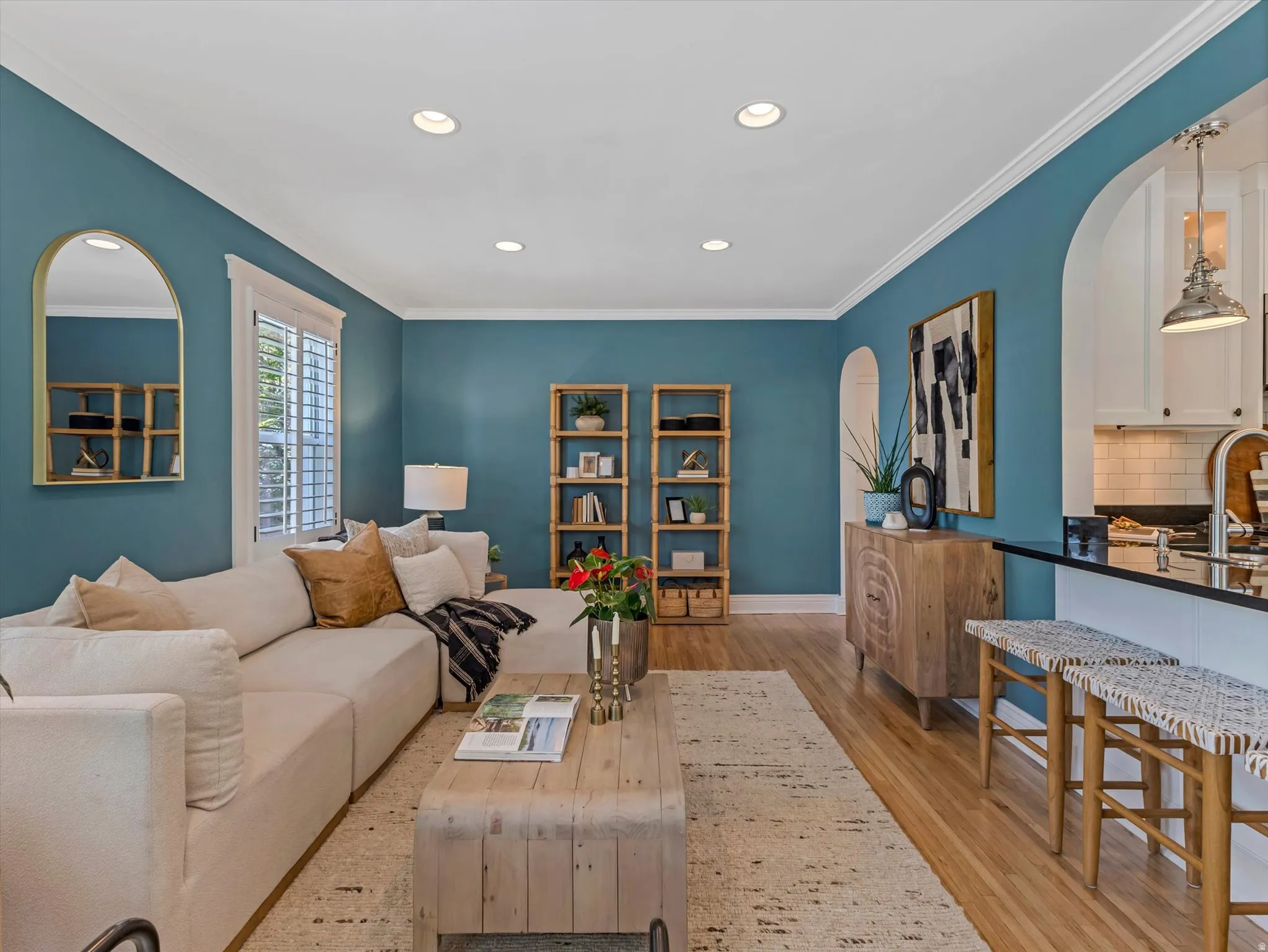 Recessed ceiling lighting, crown molding, wood-finish flooring, plantation shutters, and a kitchen pass-through with counter seating