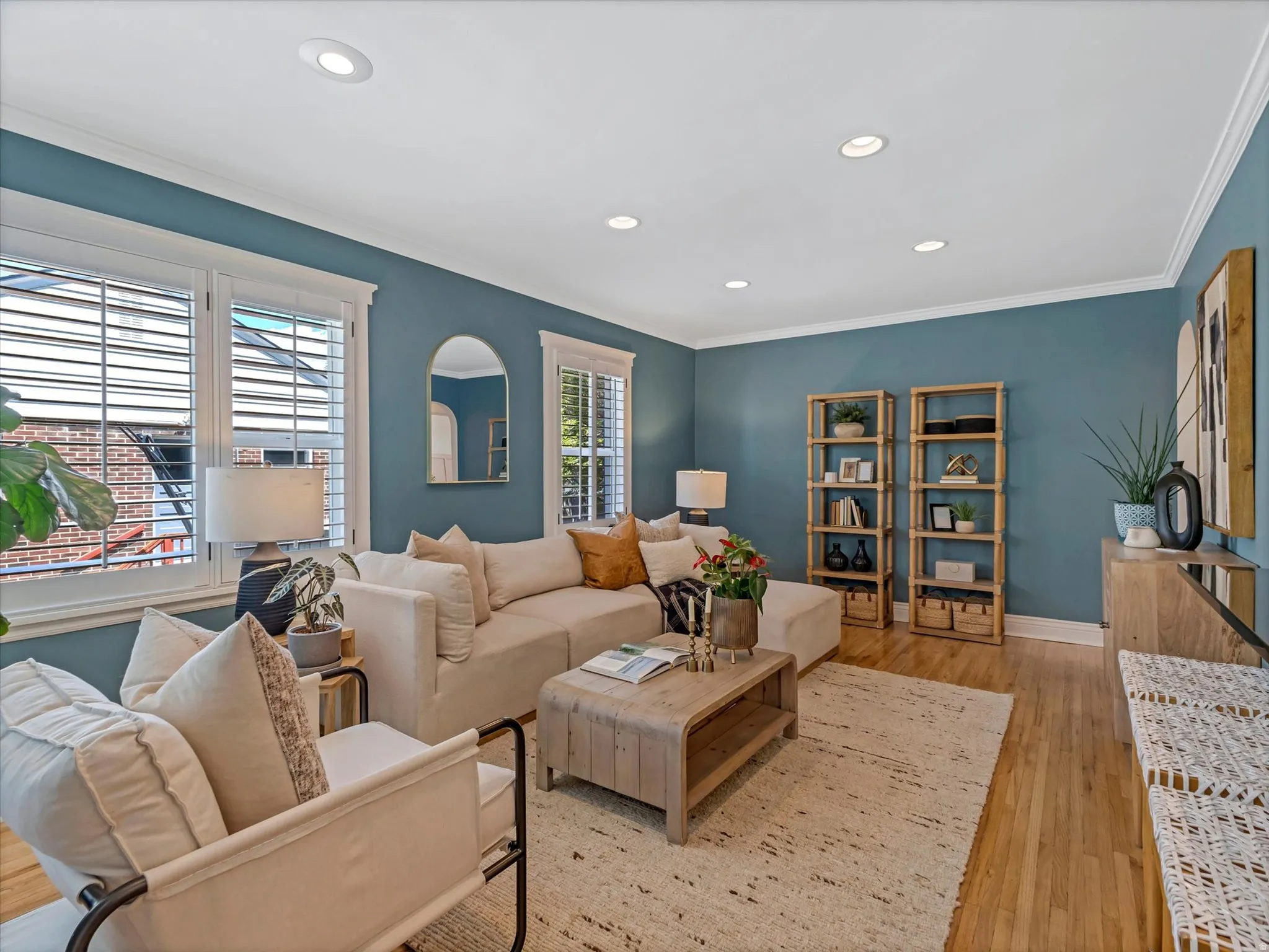 Recessed lighting with crown molding, plantation shutters, and wood-finish flooring