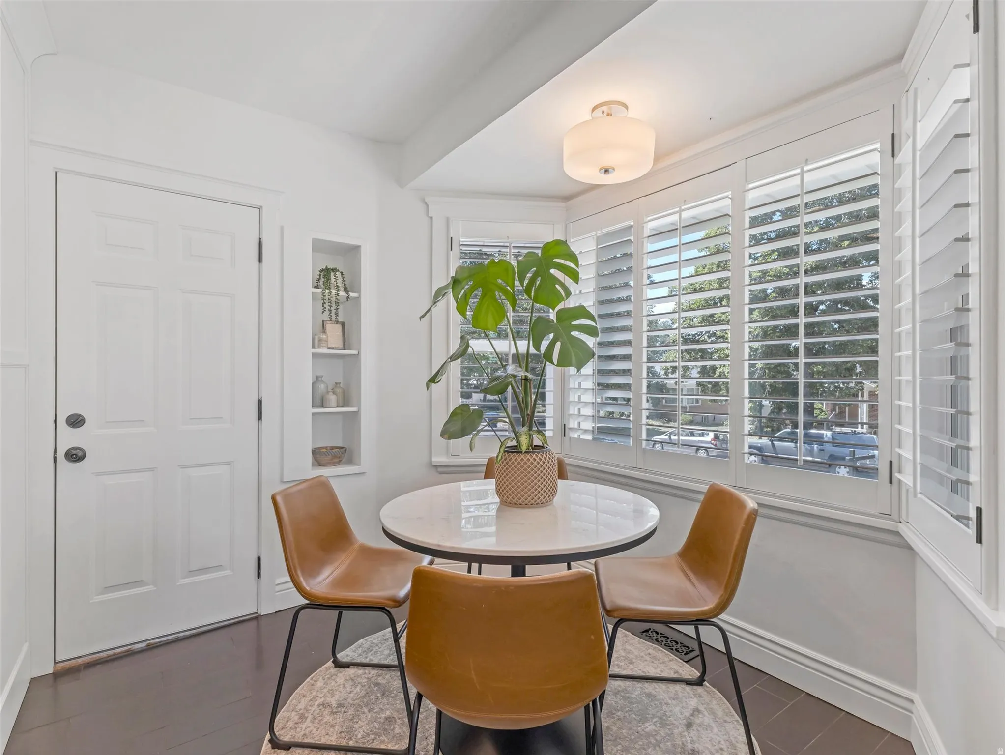 Hardwood flooring, recessed shelving, bay windows with plantation shutters, and a ceiling-mounted light fixture