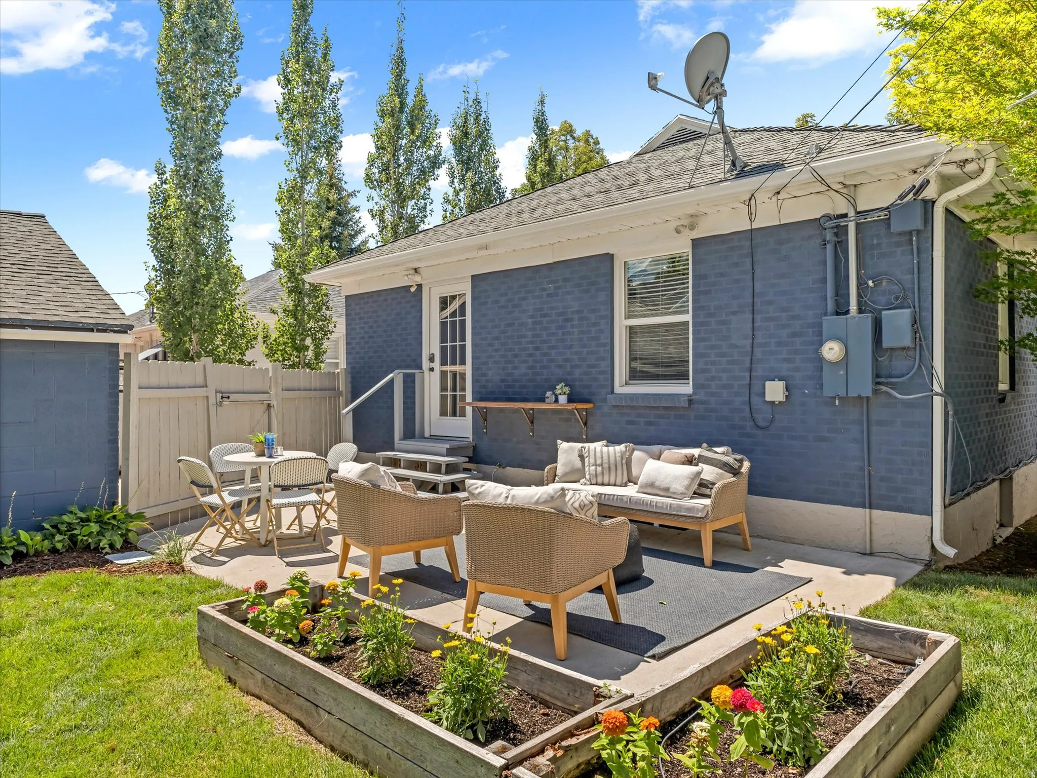 Expansive concrete patio, raised garden bed, and a manicured lawn