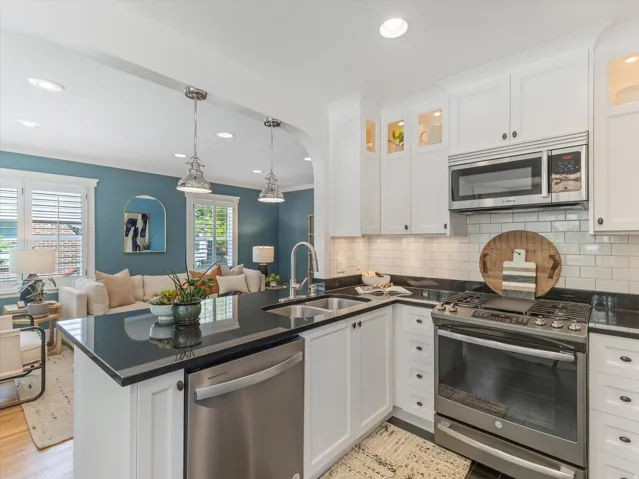 Kitchen featuring dark countertops, white cabinetry, stainless steel appliances, a subway tile backsplash, and recessed lighting