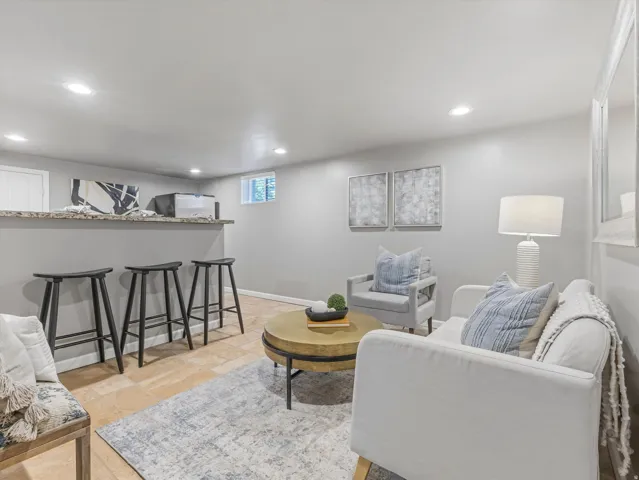 Recessed ceiling lighting, built-in bar with stone-finish countertop, durable tile flooring, egress window, and neutral wall tones