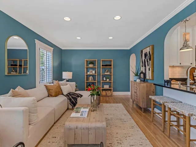 Recessed ceiling lighting, crown molding, wood-finish flooring, plantation shutters, and a kitchen pass-through with counter seating