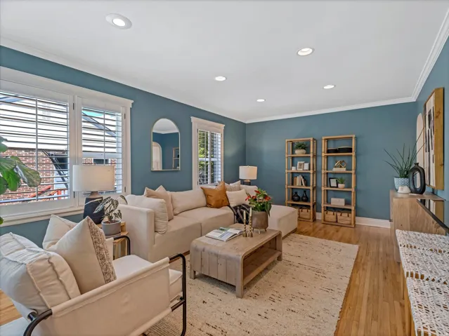 Recessed lighting with crown molding, plantation shutters, and wood-finish flooring