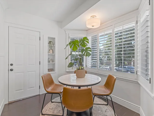 Hardwood flooring, recessed shelving, bay windows with plantation shutters, and a ceiling-mounted light fixture