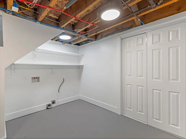 Painted concrete flooring, white walls, built-in shelving, two overhead light fixtures, and white paneled bi-fold doors