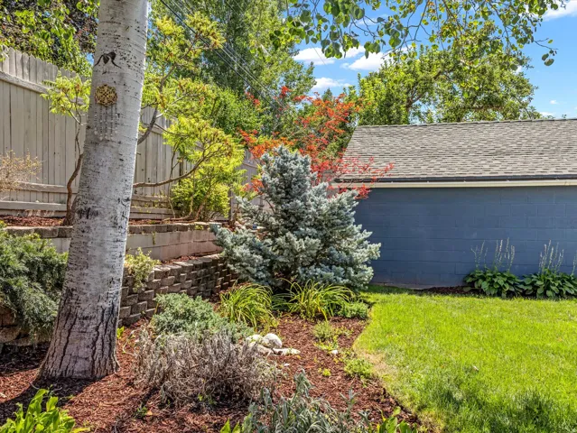 Manicured landscaping with mature trees, layered retaining walls, lush ground cover, and a well-maintained lawn