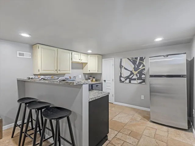 Breakfast bar with granite-style countertop, recessed lighting, and tile flooring