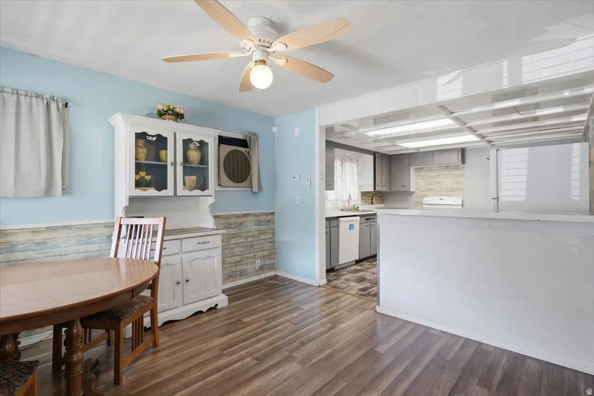 Open-concept kitchen and dining area featuring wood-finish flooring, light blue accent walls, and abundant natural light from multiple windows
