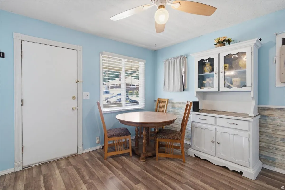 Interior space featuring wood-finish flooring, light blue wall paint, and a textured lower wall paneling
