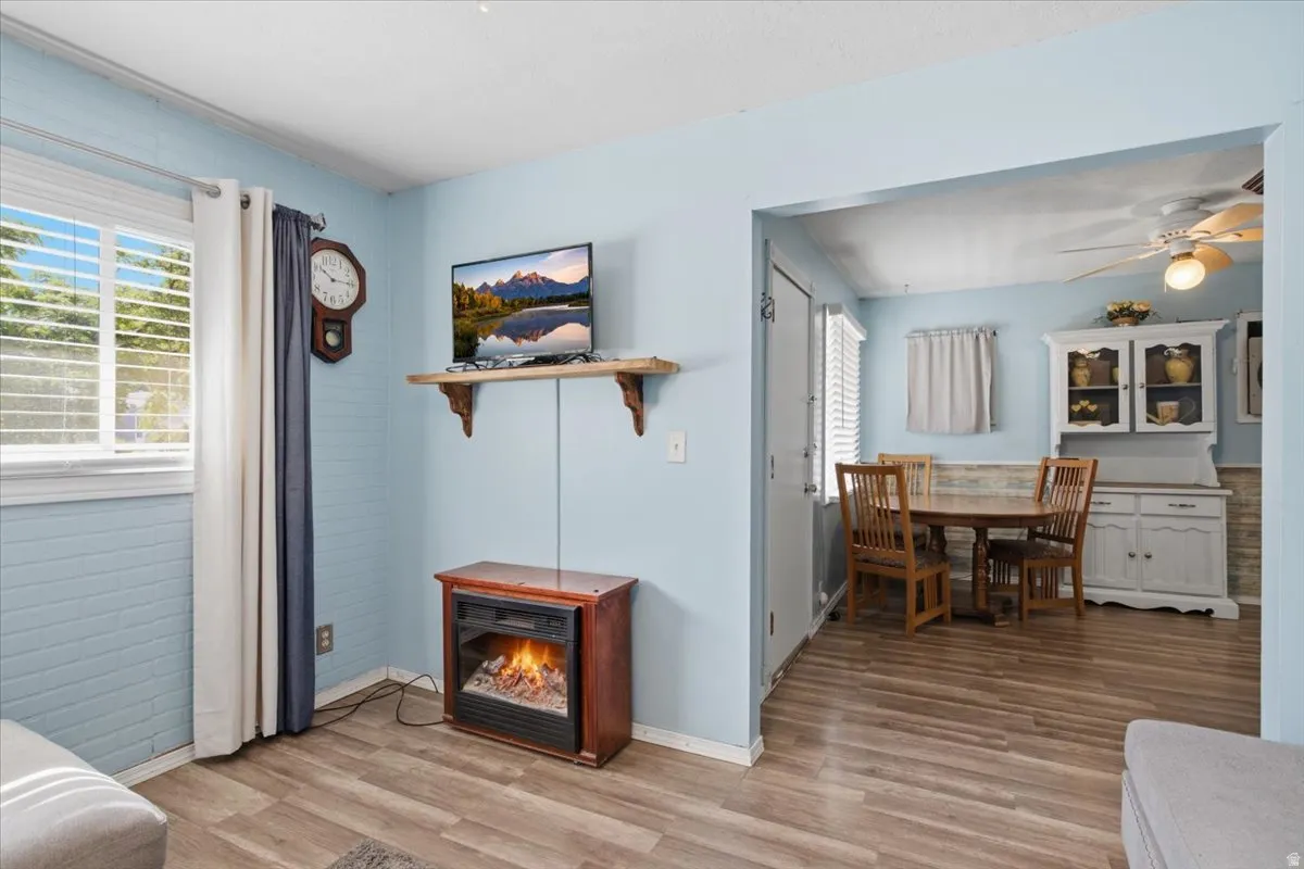 Open-concept living space featuring wood-finish flooring, light blue accent walls, and a wood-burning stove with red surround