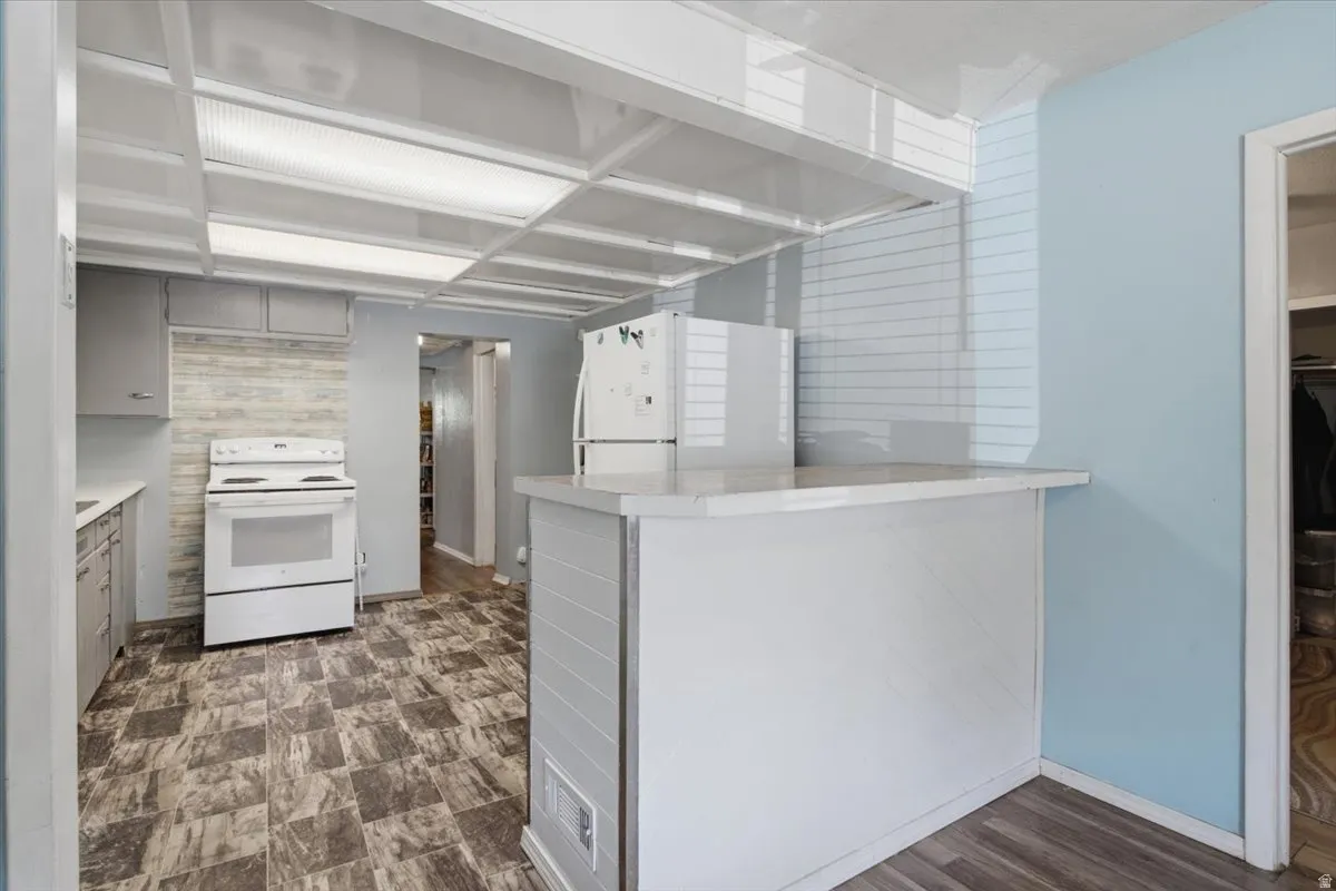 Kitchen featuring a breakfast bar with a white countertop, wood-finish flooring, and a white electric range