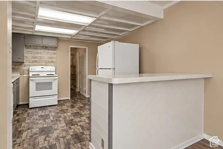 Kitchen featuring white appliances, a breakfast bar with a light-colored countertop, and patterned floor tiles