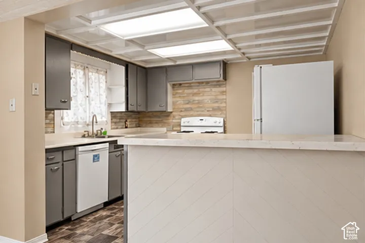 Kitchen featuring shaker-style cabinetry, wood-finish flooring, a white dishwasher, and a stone backsplash