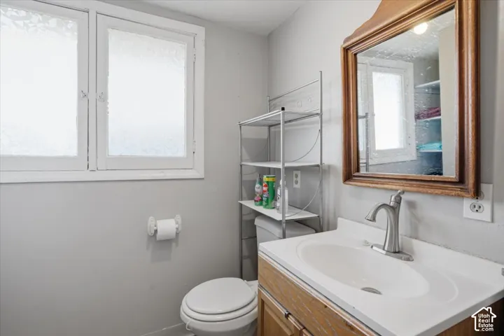 Bathroom featuring a wood-finish vanity with an integrated sink, a wall-mounted mirror with a decorative frame, and a dual-pane window