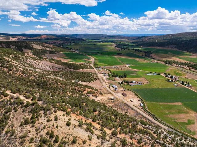 Expansive land featuring a valley floor, agricultural fields, and wooded hillsides