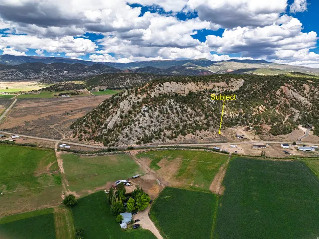 Rural landscape with expansive fields, distant mountain ranges, and a prominent rocky hillside